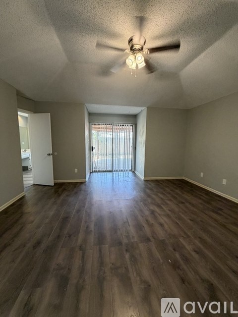 A spacious room with a ceiling fan and wooden flooring.