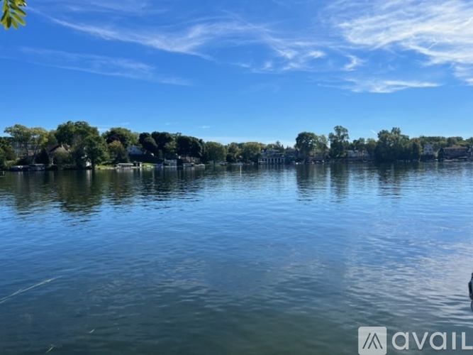 A calm lake with trees and a clear sky.