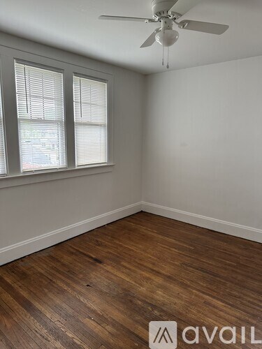 A room with a ceiling fan and wooden flooring.