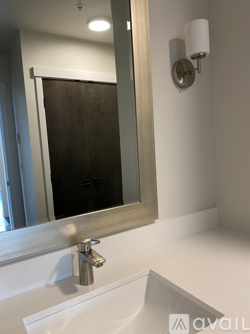 A bathroom sink with a mirror above it and a wall light to the side.