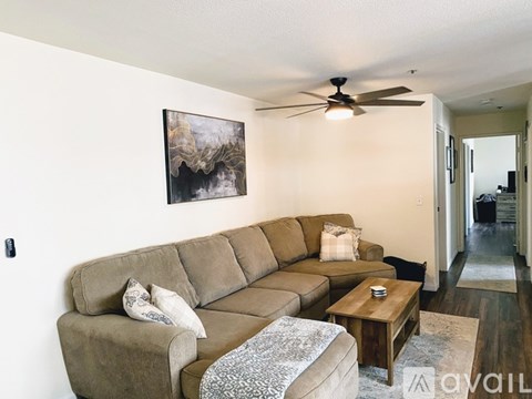 A living room with a brown couch and a painting on the wall.
