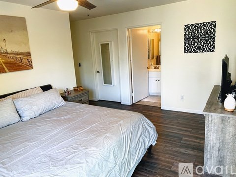 A bedroom with a large bed and a painting on the wall.