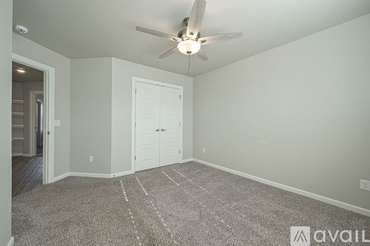 A room with a ceiling fan and a rug on the floor.