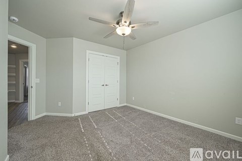A room with a ceiling fan and a rug on the floor.