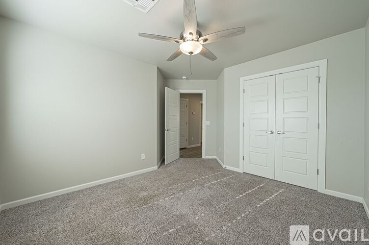 A room with a ceiling fan and carpeted floor.