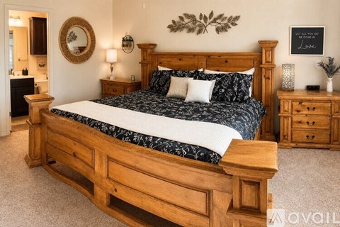 A bedroom with a large bed, wooden furniture, and a mirror on the wall.