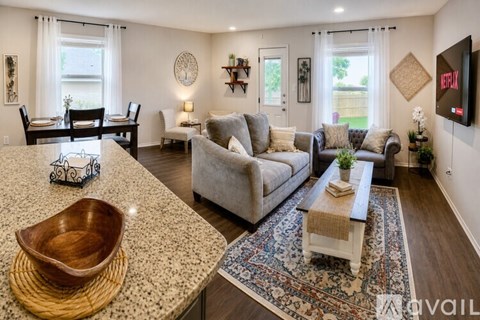 A living room with a grey couch and a wooden bowl on the table.