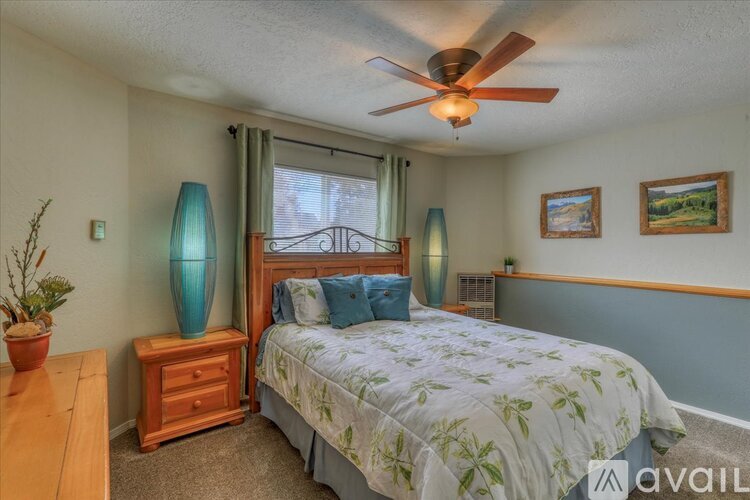 A bedroom with a bed, nightstand, and a ceiling fan.