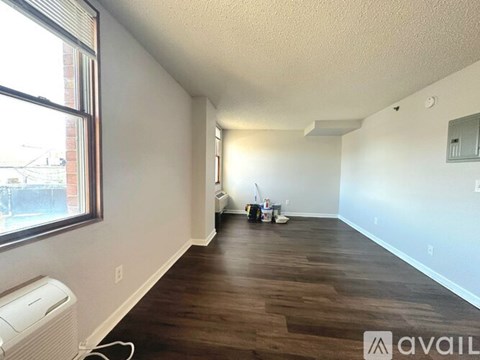 A room with wooden flooring and a window on the left side.