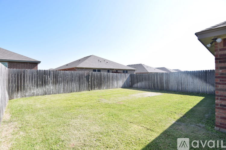 A backyard with a wooden fence and a house in the background.