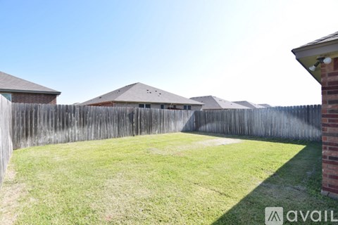 A backyard with a wooden fence and a house in the background.