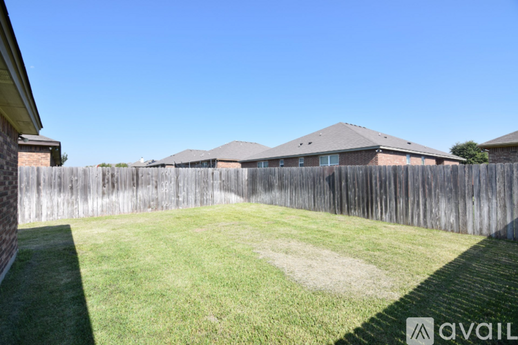 A backyard with a wooden fence and a green lawn.
