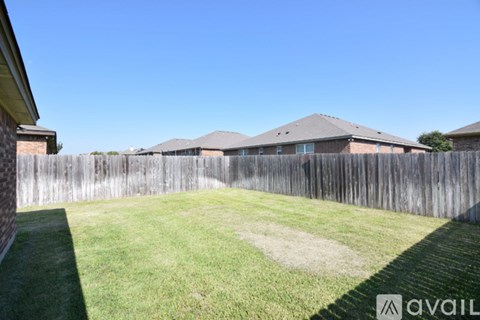 A backyard with a wooden fence and a green lawn.