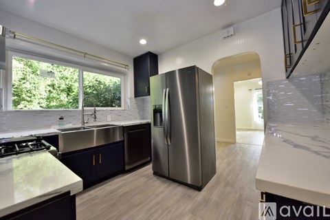 A modern kitchen with a stainless steel refrigerator and a marble countertop.