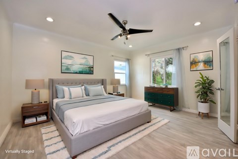 A bedroom with a large bed and a ceiling fan.