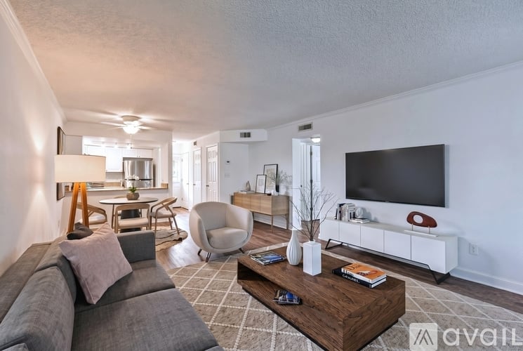 A living room with a grey couch, a wooden coffee table, and a white TV stand.