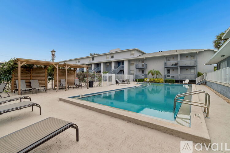 A pool area with sun loungers and a building in the background.
