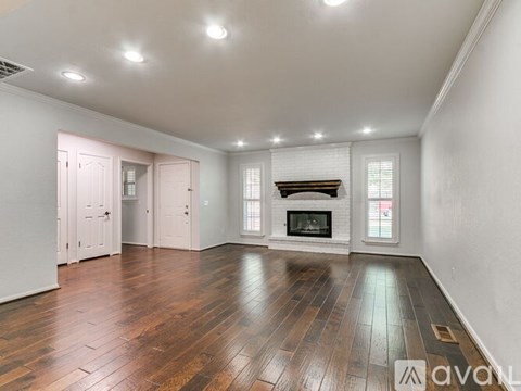 A spacious room with wooden floors and a fireplace.