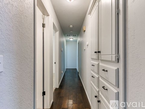 A long hallway with white walls and wooden floors.