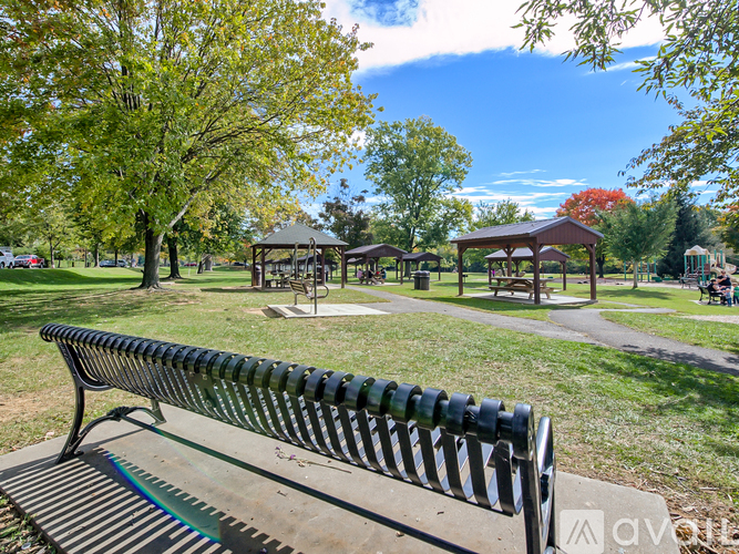 A park bench is in the foreground with a gazebo in the background.