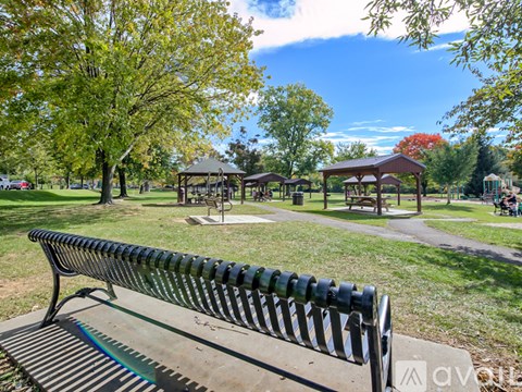 A park bench is in the foreground with a gazebo in the background.