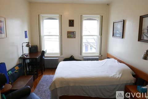 A bedroom with a large bed and two windows.