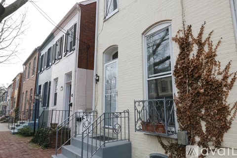 A white building with a black iron railing on the steps.