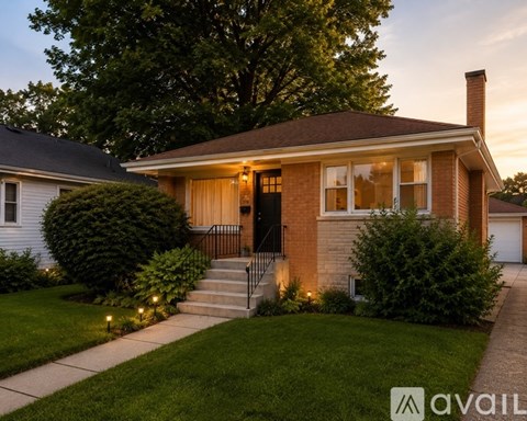 A house with a front yard and a tree in the background.