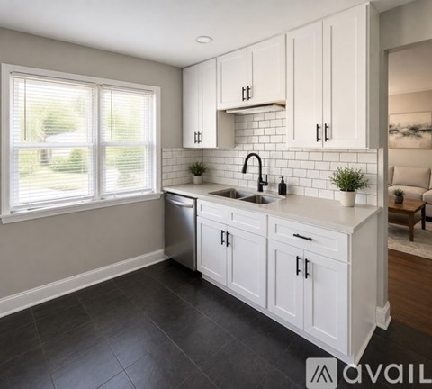 A kitchen with white cabinets and a black countertop.