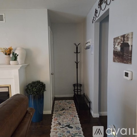 A hallway with a floral runner, a brown couch, and a blue vase.