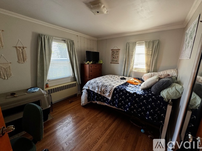A bedroom with a bed, a chair, and a window.