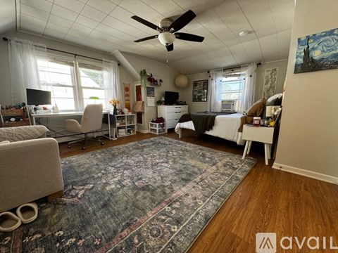 A living room with a rug on the floor and a ceiling fan above.