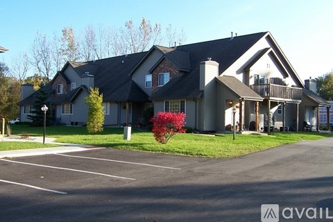 A large house with a grey roof and a parking lot in front.