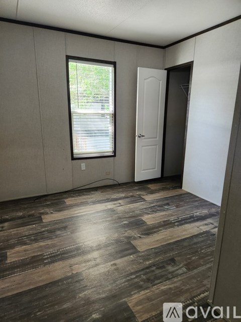 A room with wooden flooring and a window with blinds.
