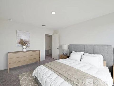 A bedroom with a large bed and a wooden dresser.