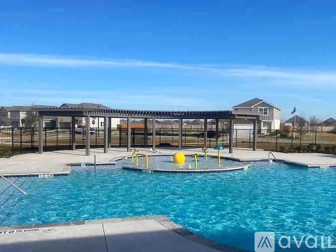 A large outdoor swimming pool with a diving board and a fence surrounding the area.