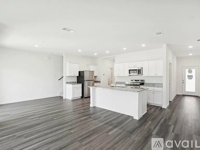A spacious kitchen with white cabinets and a wooden floor.