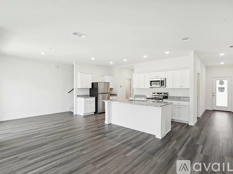 A spacious kitchen with white cabinets and a wooden floor.