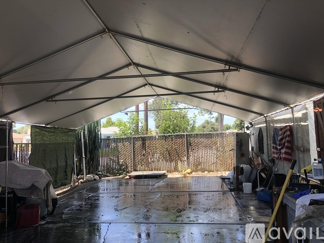 A large white tent with a wet floor and a fence in the background.