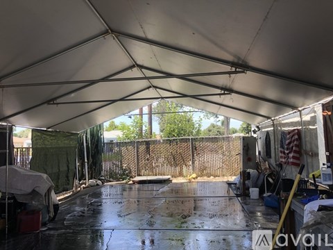A large white tent with a wet floor and a fence in the background.