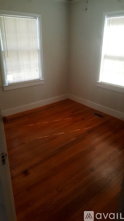 A room with wooden floors and two windows.