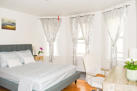 A bedroom with a bed, chair, and table.