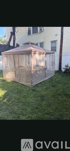 A large, beige-colored greenhouse is situated in a grassy area.