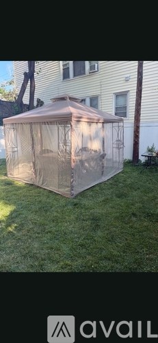A large, beige-colored greenhouse is situated in a grassy area.