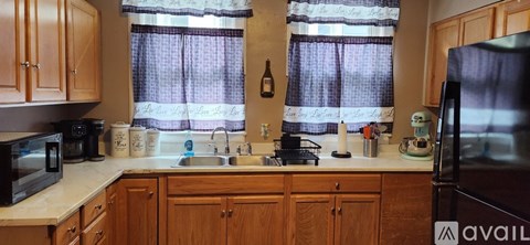 A kitchen with wooden cabinets and a black refrigerator.