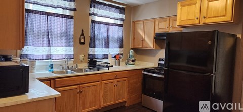 A kitchen with wooden cabinets and a black refrigerator.