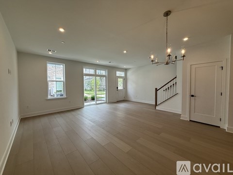 A spacious room with wooden flooring and a chandelier.