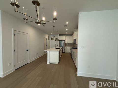 A modern kitchen with white cabinets and a wooden floor.