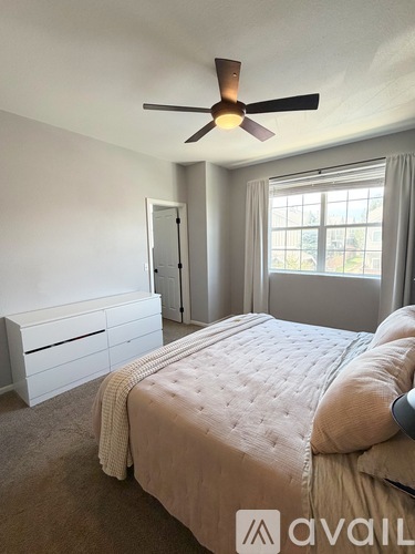 A bedroom with a large bed and a ceiling fan.