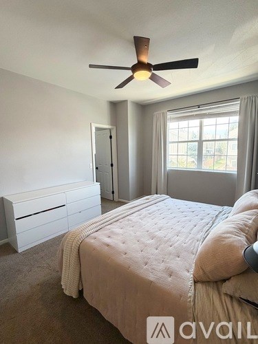 A bedroom with a large bed and a ceiling fan.